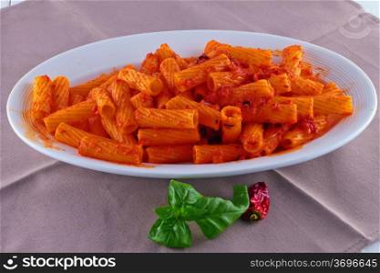 A plate full of tortiglioni with sauce, pepper and basil