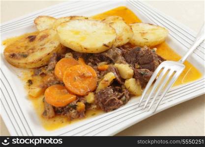 A plate of British style beef stew served with sauteed sliced potatoes, a traditional winter warmer.