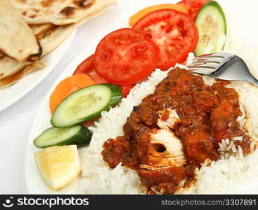 a plate of chicken tikka masala, served with white rice, a side salad and flat chapatti or naan bread.