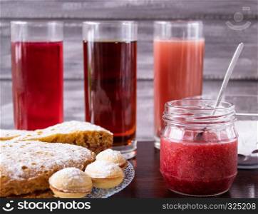A plate of delicious cookies with berries, nuts, jam and apple juice on the table, selective focus.