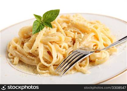 A plate of Fettucine all&acute;Alfredo, pasta in a butter, cream and parmesan sauce, garnished with a sprig of basil and sprinkled with grated cheese