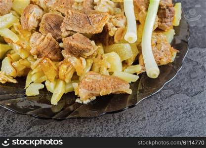 A plate of fried meat with potatoes on a stone table