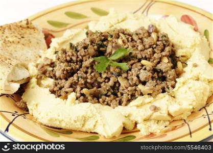 A plate of hummus chickpea dip filled with fried lamb mince, onion, pine nuts and parsley, known as hummus bil lahme.