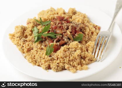 A plate of Lebanese burghul bi banadoura, or cracked wheat with tomatoes. The dish incorporates onion, minced meat and pine nuts, along with the burghul or bulgar wheat.