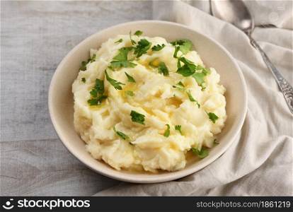 A plate of mashed potatoes poured with melted butter and seasoned with greens