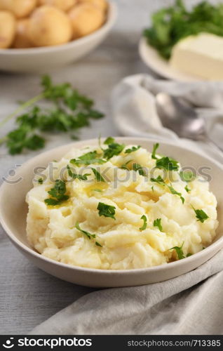 A plate of mashed potatoes poured with melted butter and seasoned with greens