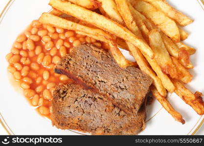 A plate of meatloaf served with baked beans and chips or french fries viewed from above.