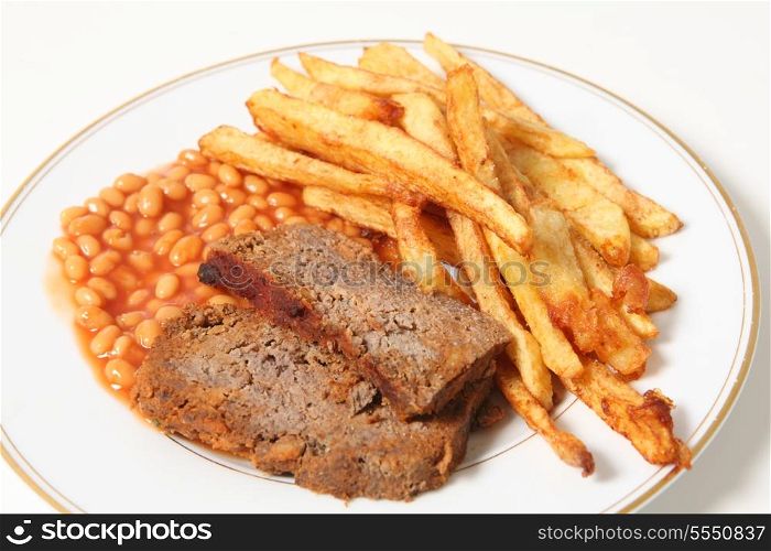 A plate of meatloaf served with baked beans and chips or french fries.