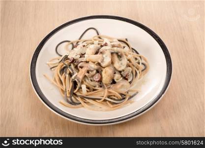 A plate of mixed types of spaghetti with a white mushroom and olive sauce.