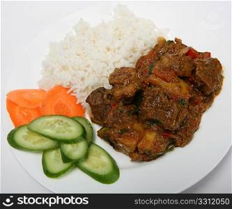 A plate of mutton vindaloo curry with rice and salad, viewed close-up