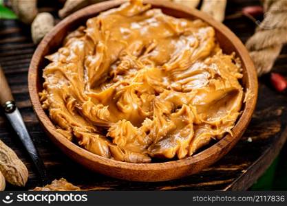 A plate of peanut butter on a wooden background. High quality photo. A plate of peanut butter on a wooden background.