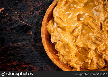 A plate of peanut butter on the table. On a rustic dark background. High quality photo. A plate of peanut butter on the table.