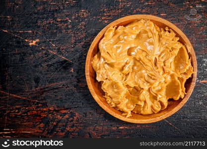 A plate of peanut butter on the table. On a rustic dark background. High quality photo. A plate of peanut butter on the table.