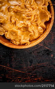 A plate of peanut butter on the table. On a rustic dark background. High quality photo. A plate of peanut butter on the table.