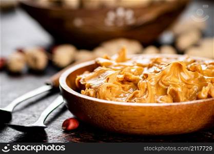 A plate of peanut butter on the table. On a rustic dark background. High quality photo. A plate of peanut butter on the table.