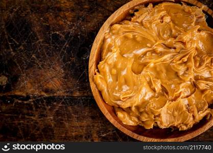 A plate of peanut butter on the table. On a rustic dark background. High quality photo. A plate of peanut butter on the table.