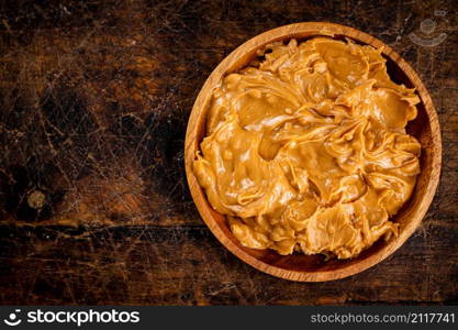 A plate of peanut butter on the table. On a rustic dark background. High quality photo. A plate of peanut butter on the table.