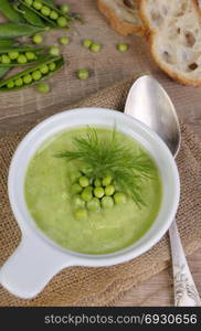 A plate of soup puree of green peas with dill on a table