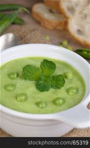 A plate of soup puree of green peas with mint on a table