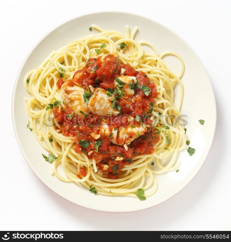 A plate of Spaghetti all?arrabbiata with fish, garnished with chopped parsley, seen from above.