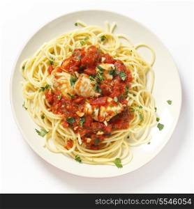A plate of Spaghetti all?arrabbiata with fish, garnished with chopped parsley, seen from above.