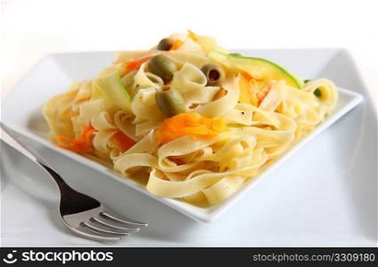 A plate of tagliatelle with ribbons of carrot and courgette, stuffed olives and a sprinkling of black pepper, tossed in a garlic flavoured olive oil,