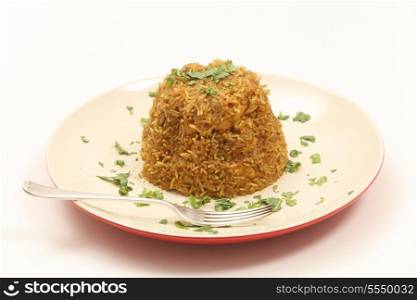A plate of traditional Indian chicken biryani, garnished with coriander (cilantro) and mint leaves on a plate with a fork