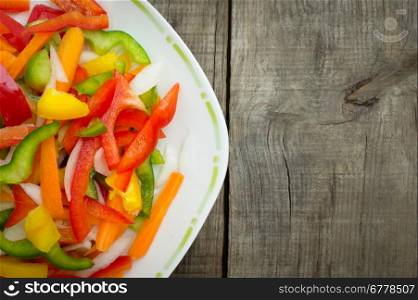 A plate of vegetable slices on wood background