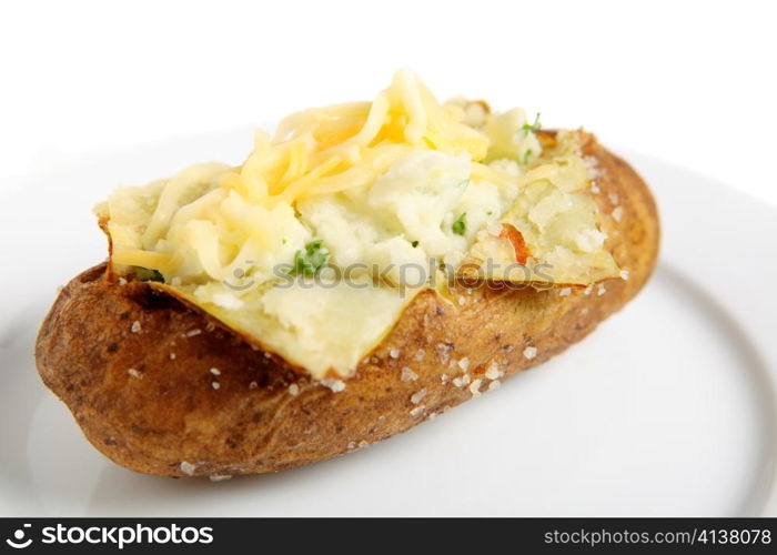 A plate with a baked idaho russet potato split open and creamed with butter and fresh parsley, topped with mixed cheddar and mozarella cheeses