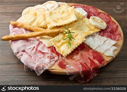a platter of mixed cured meats, cheeses and fried dumpling