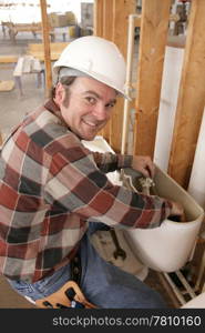 A plumber repairing a toilet on a construction site.