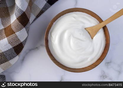 A portion of Greek yogurt in a wooden bowl ready to be served. Healthy food for dieting concept.