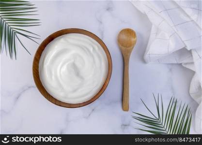 A portion of Greek yogurt in a wooden bowl ready to be served. Hea<hy food for dieting concept.