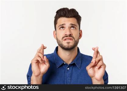 A portrair of a young man with crossed fingers and closed eyes praying for risky business. A portrair of a young man with crossed fingers and closed eyes praying for risky business.