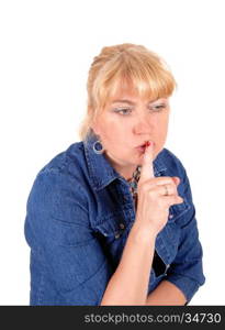 A portrait image of a pretty blond woman in a jeans jacket, holding herfinger over her mouth, isolated for white background.