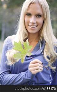 A portrait of a beautiful caucasian woman holding an autumn leaf
