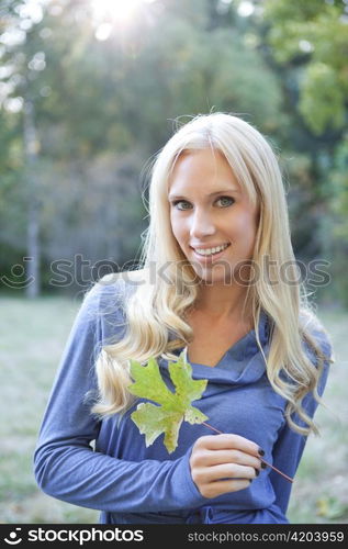 A portrait of a beautiful caucasian woman holding an autumn leaf