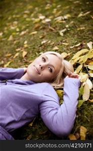 A portrait of a beautiful caucasian woman lying down on autumn leaves on the ground