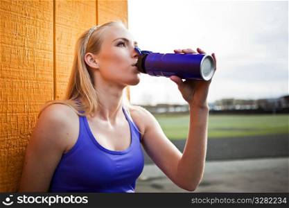A portrait of a beautiful sporty caucasian woman drinking water