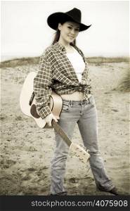 A portrait of a beautiful young woman carrying a guitar in sepia tone