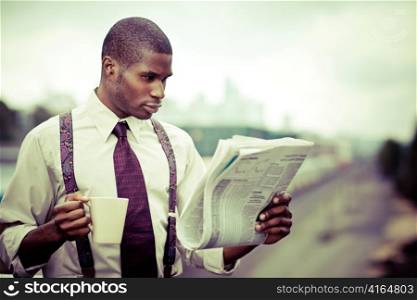 A portrait of a black businessman reading newspaper outdoor