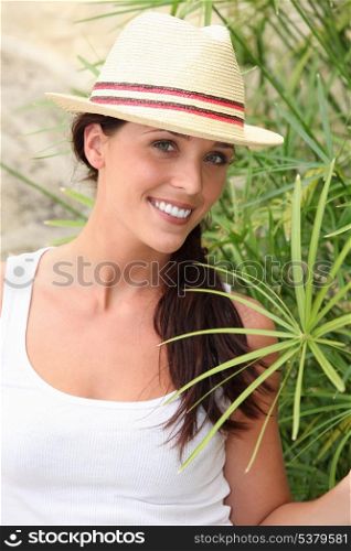 A portrait of a cute brunette by a plant.