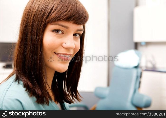 A portrait of a dental hygienist in front of a dental chair