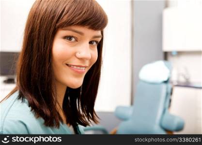 A portrait of a dental hygienist in front of a dental chair