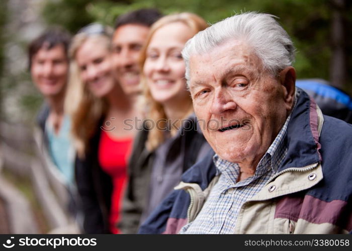 A portrait of a grandfather type man with a group of young people