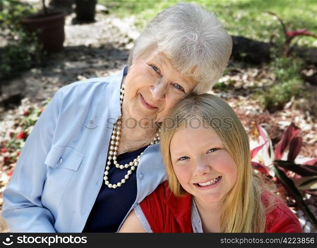 A portrait of a grandmother and granddaughter in the garden. Horizontal composition with room for text.