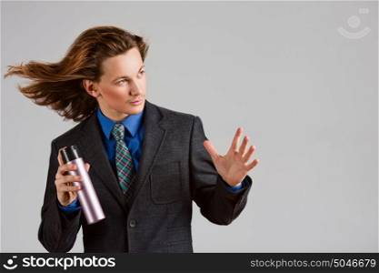 A portrait of a handsome long-haired man in suit holding a bottle of hair spray.