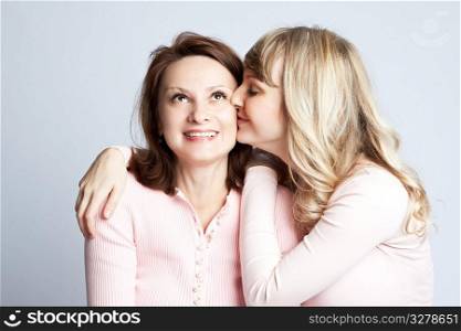A portrait of a happy daughter kissing her mother