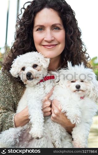 A portrait of a happy mature woman with her dogs outdoor