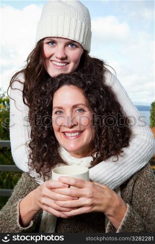 A portrait of a happy mother and daughter drinking coffee outdoor